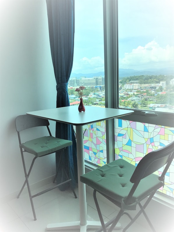 Enjoy a serene city view from the comfort of this stylish room, featuring a table, two chairs, and a large window.