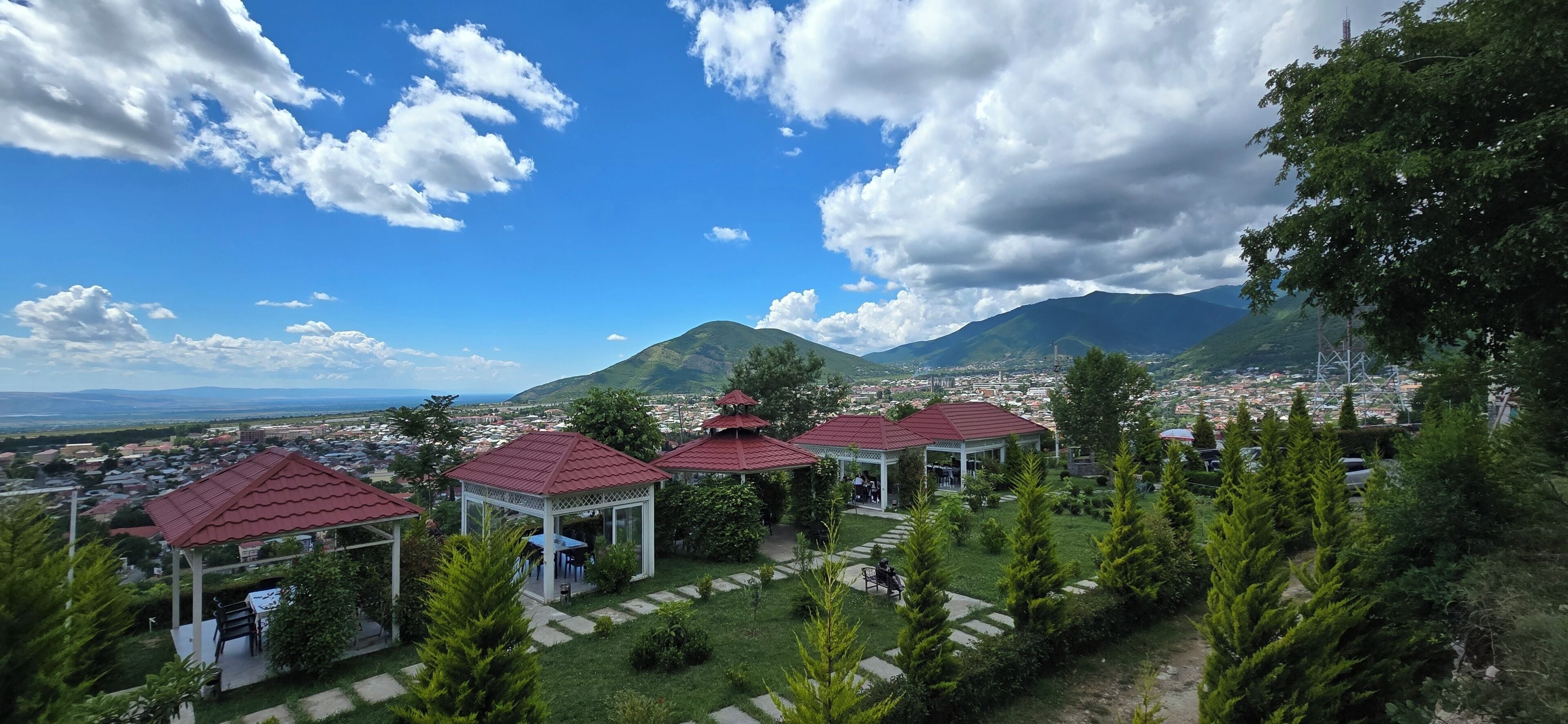 A view of a town with red-roofed gazebos and a mountain in the background.