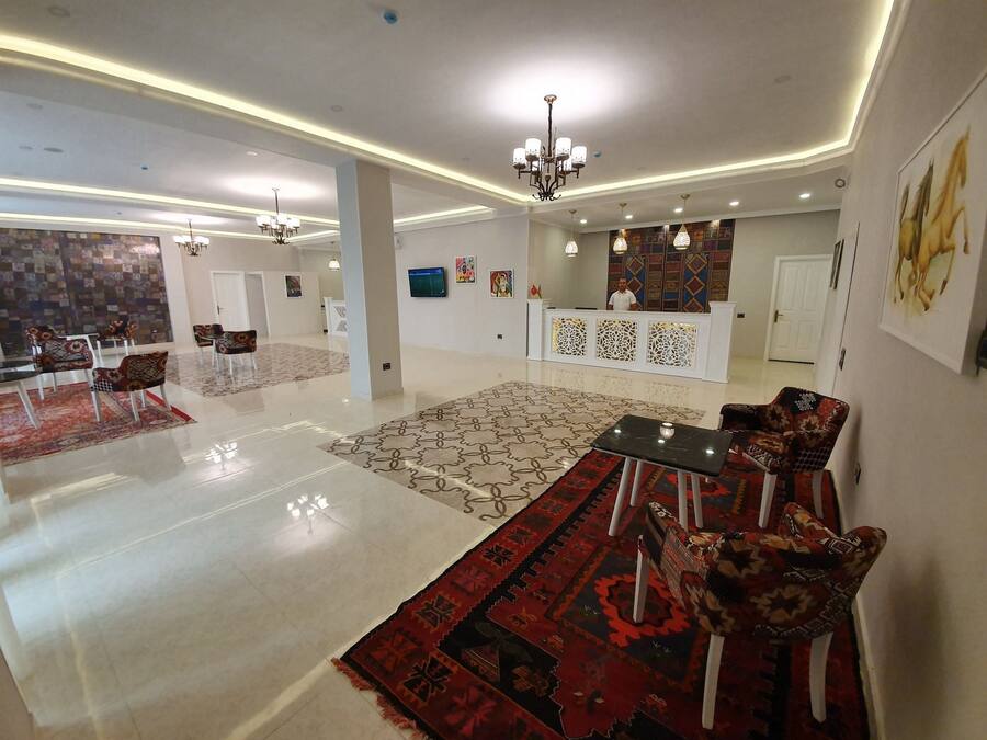 A spacious lobby with a reception desk, patterned rugs, and modern lighting fixtures.