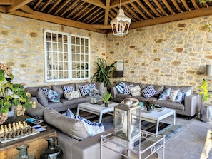 A cozy living room with stone walls, a large window, and a chessboard on a coffee table.