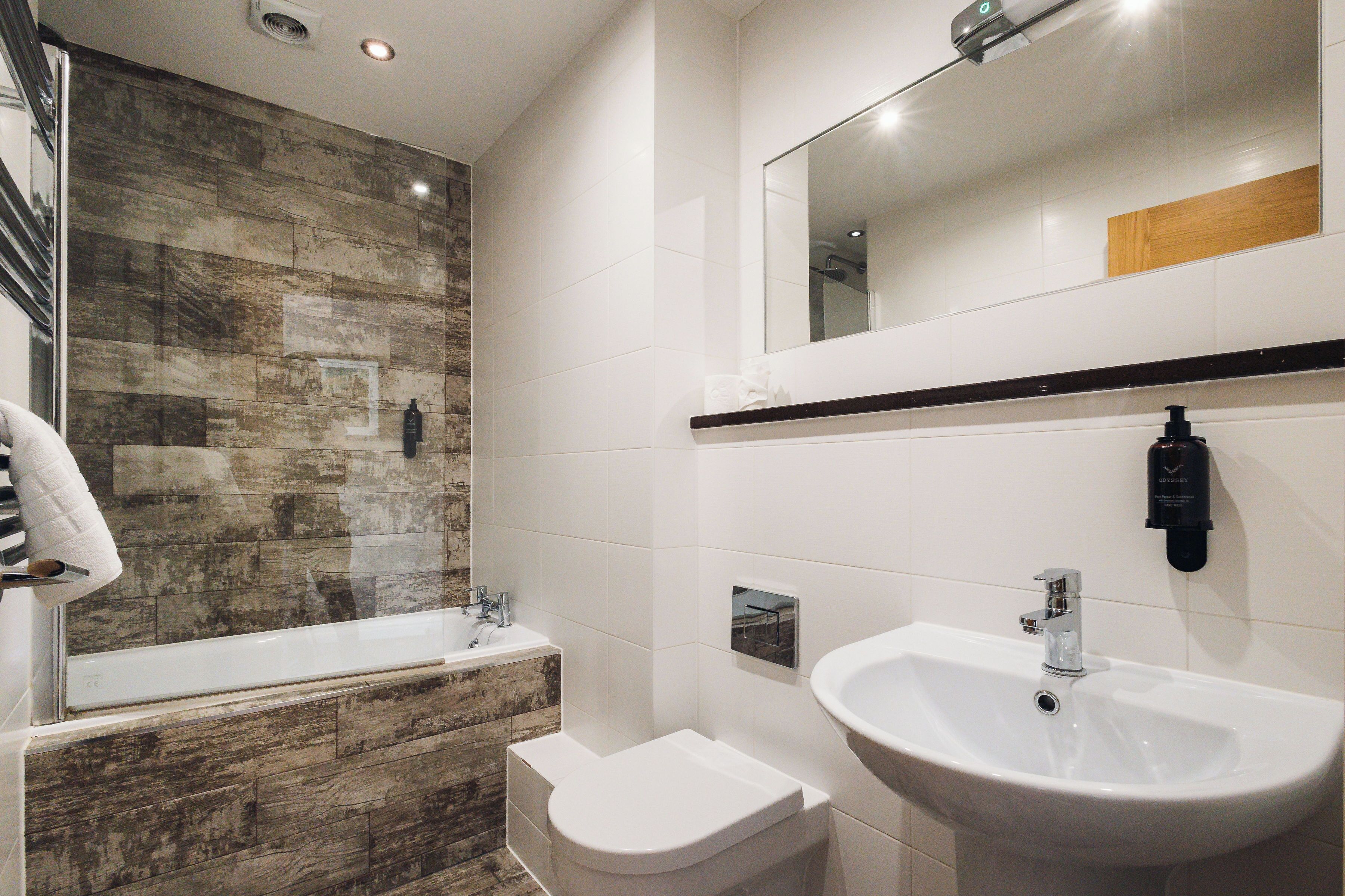 A modern bathroom with a bathtub, a toilet, a sink, and a mirror.