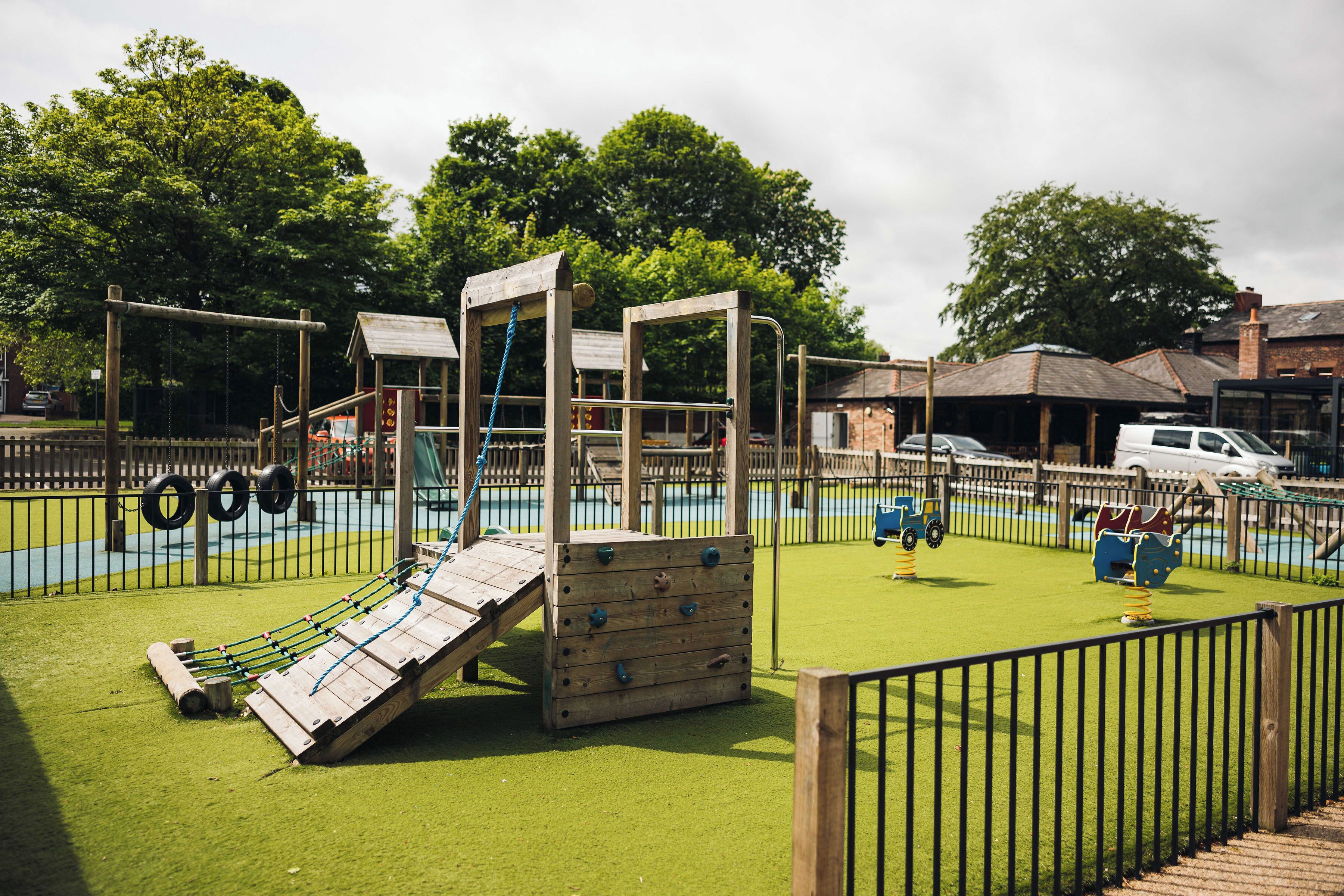 A playground with climbing structures, a slide, and a small bridge.