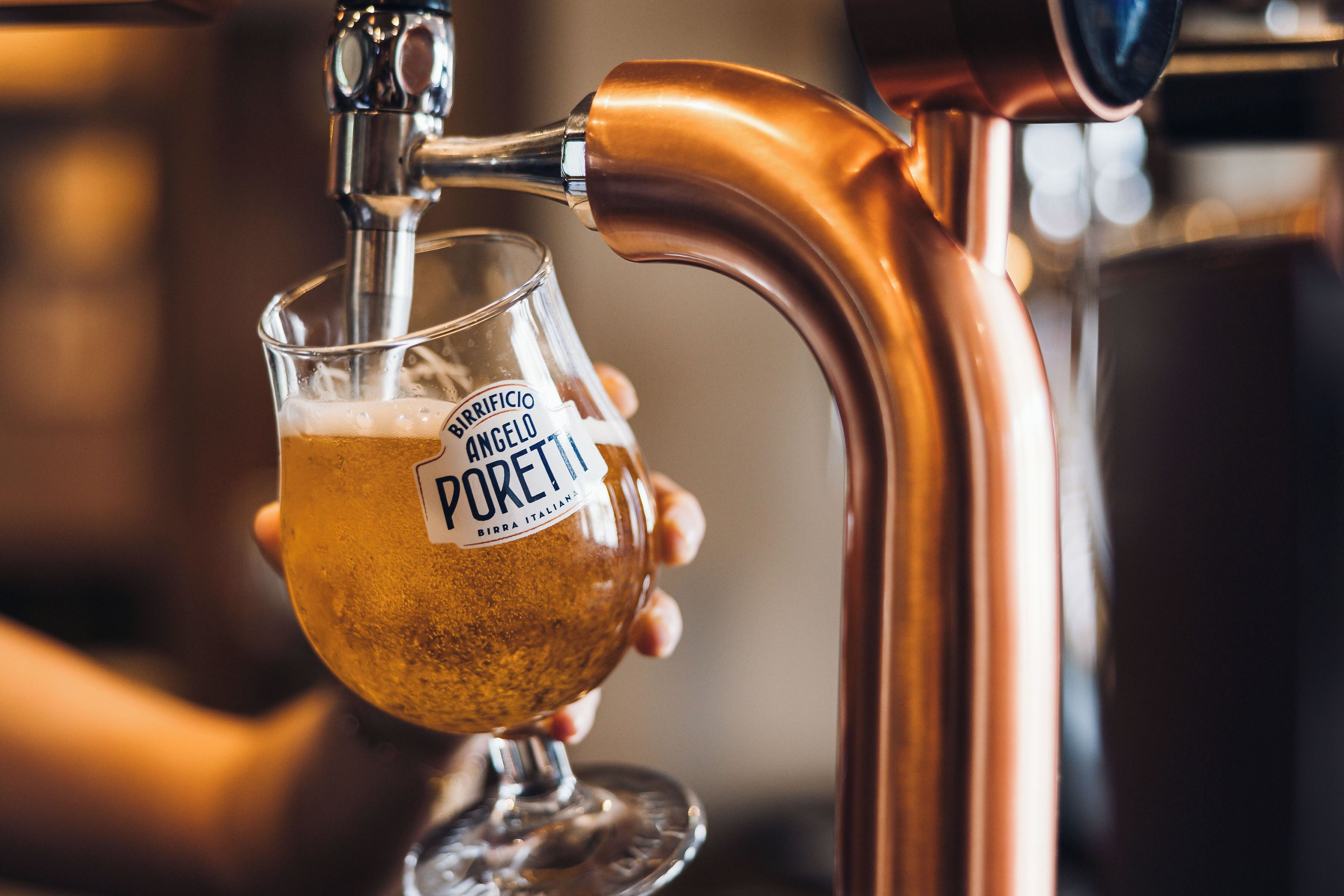 A glass of beer being poured from a tap.