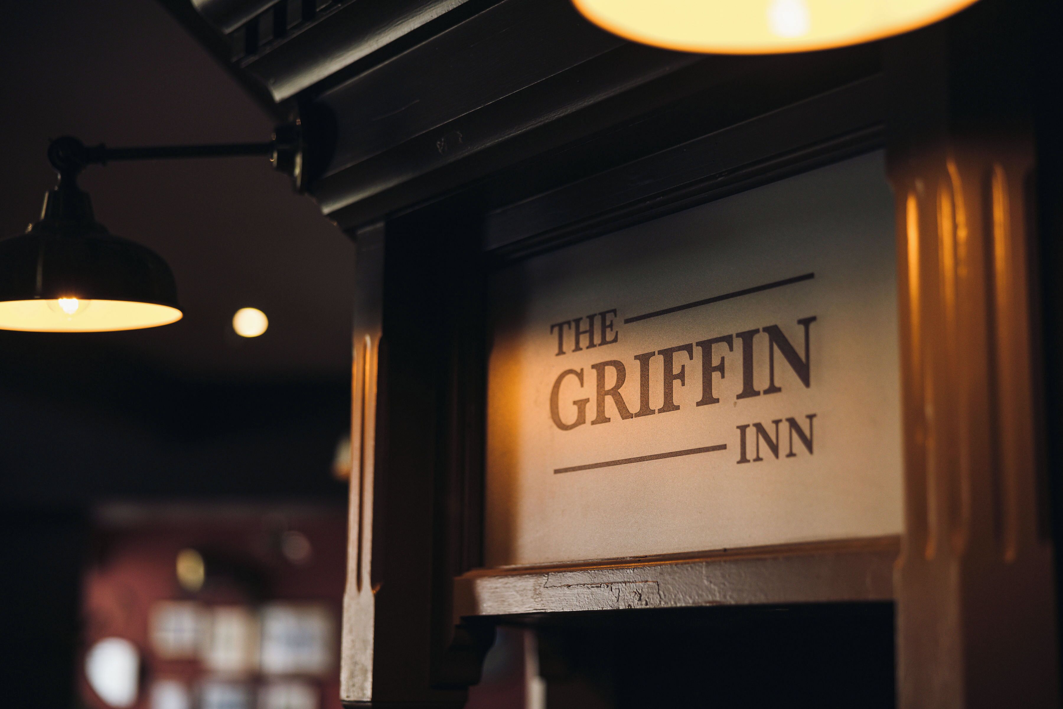 A sign for 'The Griffin Inn' with a classic design, including a lamp above it.