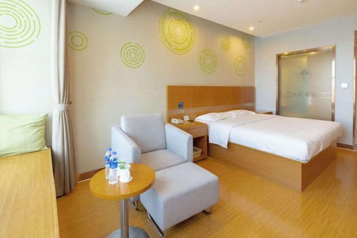 Habitación de hotel con dos camas, una mesita con botellas de agua, una silla y cabecera con teléfono.