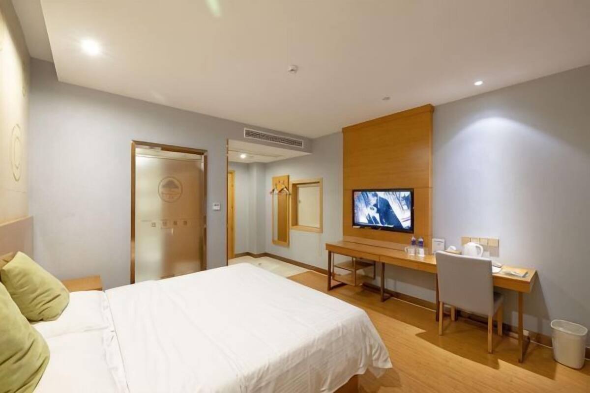 Une chambre d’hôtel avec un lit, un bureau, une télévision et un miroir.