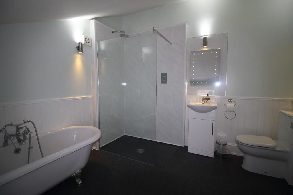 Un baño moderno con una bañera independiente, una ducha a ras de suelo, un lavabo con espejo y un inodoro.