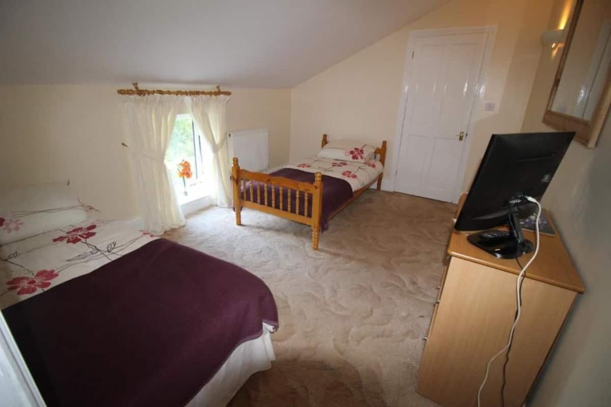 Un dormitorio con dos camas, un escritorio con computadora y una ventana con cortinas.
