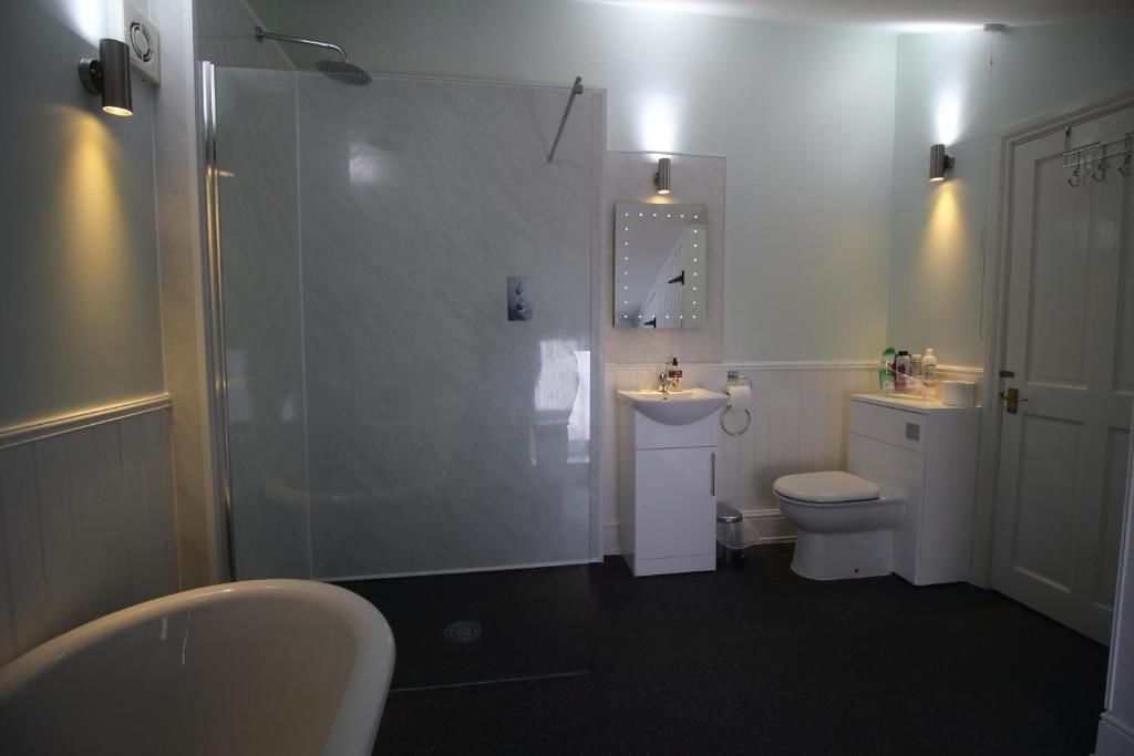 Une salle de bain avec une douche à parois de verre, un lavabo blanc, des toilettes et une baignoire.