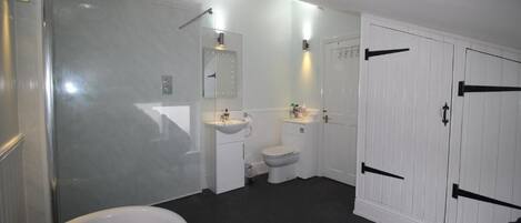 A modern bathroom with a glass-enclosed shower, a white sink, a toilet, and a bathtub.