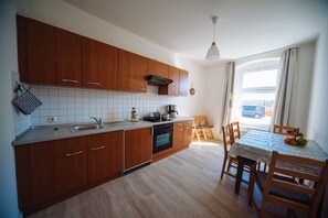 Eine moderne Küche mit Holzausstattung, einem Einbauofen und einem Essbereich mit Tisch und Stühlen.
