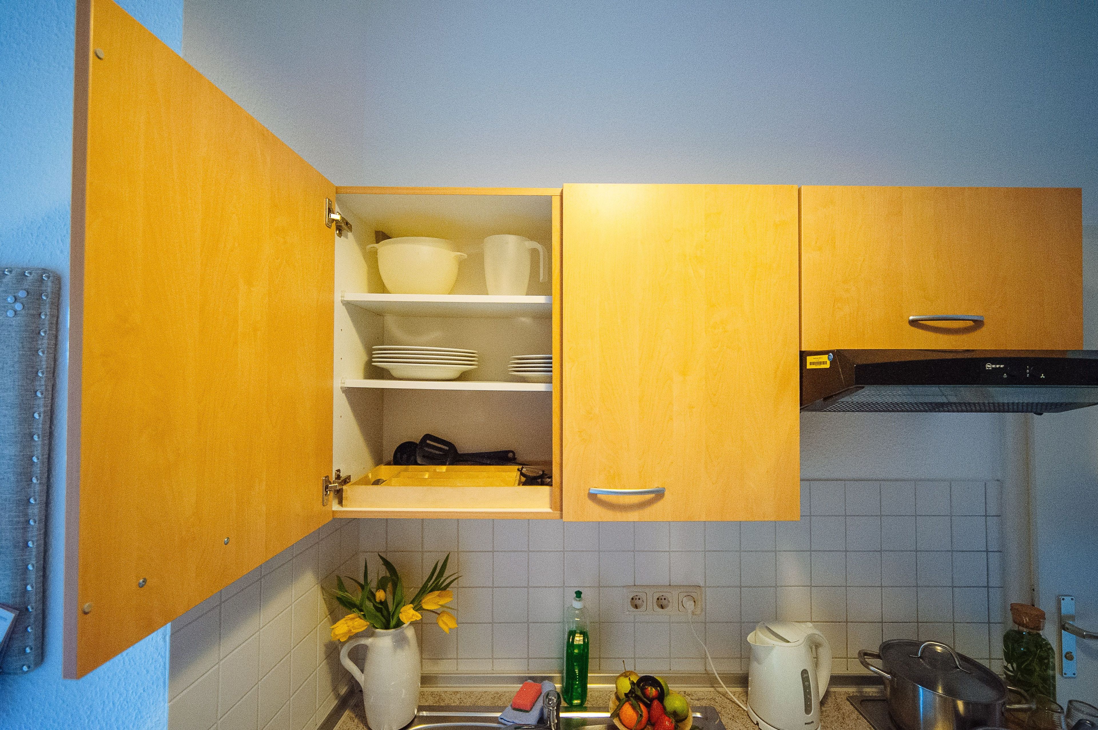 Eine Küche mit Holzausstattung, weiß gefliestem Spritzschutz, einem Spülbecken, einem Wasserkocher und verschiedenen Küchenutensilien.