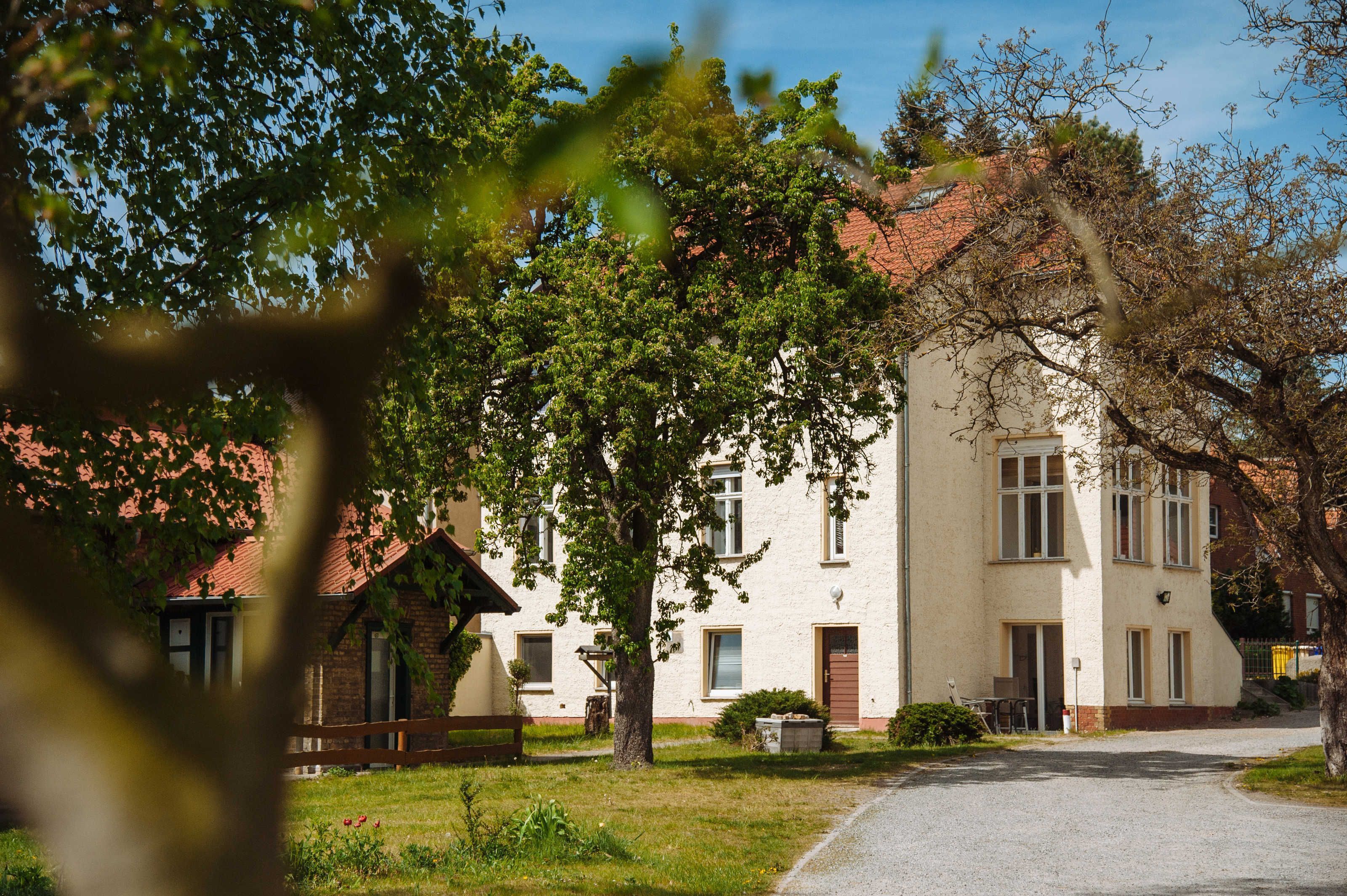 Ein zweistöckiges Gebäude mit rotem Ziegeldach, weißer Fassade und befestigter Auffahrt.