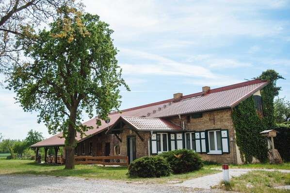 A rustic building with a sloped roof, a covered porch, and a brick exterior.