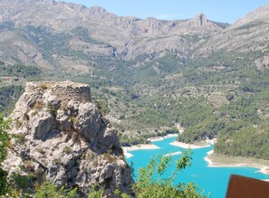 Eine Berglandschaft mit einem felsigen Vorsprung im Vordergrund und einem türkisblauen See im Hintergrund.