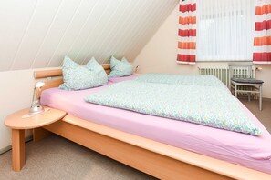 A single bed with a wooden frame, a bedside table with a lamp, and a chair.
