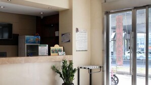 A reception area with a counter, a television, a potted plant, a bike rack, and a window with a view of the street. - GreenTree Alliance Suzhou Sports Center Xihuan Rd Hotel (Suzhou)