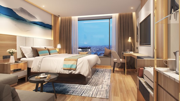 A modern hotel room with a large bed, a desk, a TV, and a view of the city. - GreenTree Alliance Suzhou Sports Center Xihuan Rd Hotel (Suzhou)