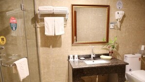 A bathroom with a glass shower, a sink with a mirror, a toilet, and a towel rack with towels. - GreenTree Inn Zaozhuang Shanting Jinke International Business Hotel (Zaozhuang)