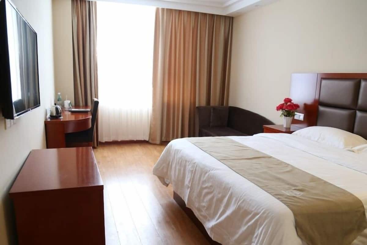 Une chambre d’hôtel avec un grand lit, un bureau, une chaise et un téléviseur.