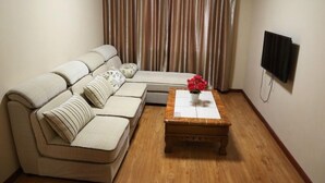 A living room with a sofa, a wooden coffee table, a TV, and a curtain. - GreenTree Inn Zaozhuang Shanting Jinke International Business Hotel (Zaozhuang)