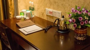 A hotel room with a wooden desk, a kettle, a vase with flowers, and toiletries on the counter. - GreenTree Inn Zaozhuang Shanting Jinke International Business Hotel (Zaozhuang)
