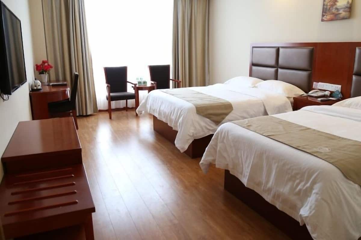 Une chambre d’hôtel avec deux lits, un bureau, une chaise et un téléviseur.