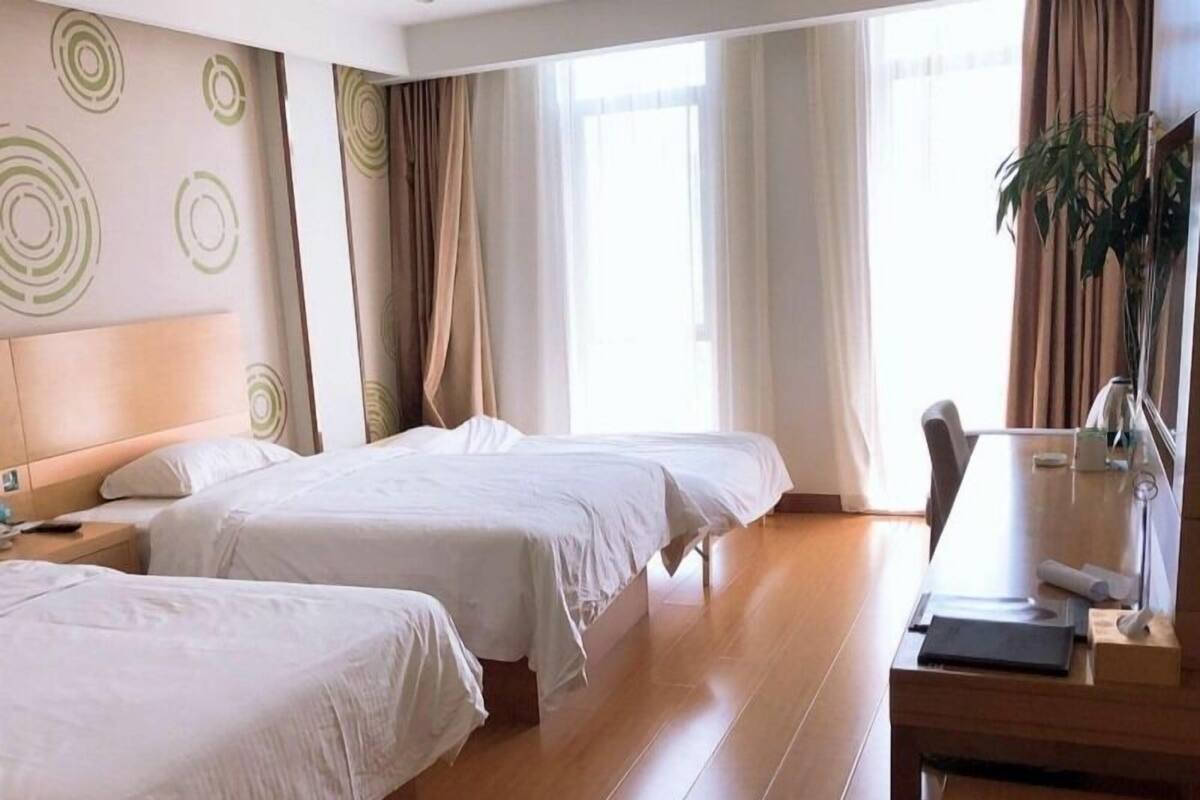 Une chambre d’hôtel avec deux lits, un bureau et une chaise.