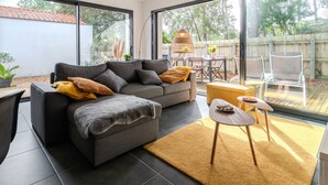 Un salon moderne avec un canapé d’angle, une petite table ronde et un coin repas comprenant des chaises et une table.