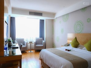 A hotel room with a bed, a desk, two chairs, a small table, and a window with curtains. - GreenTree Inn Fuyang Yingshang Yingyang Rd Business Hotel (Fuyang)