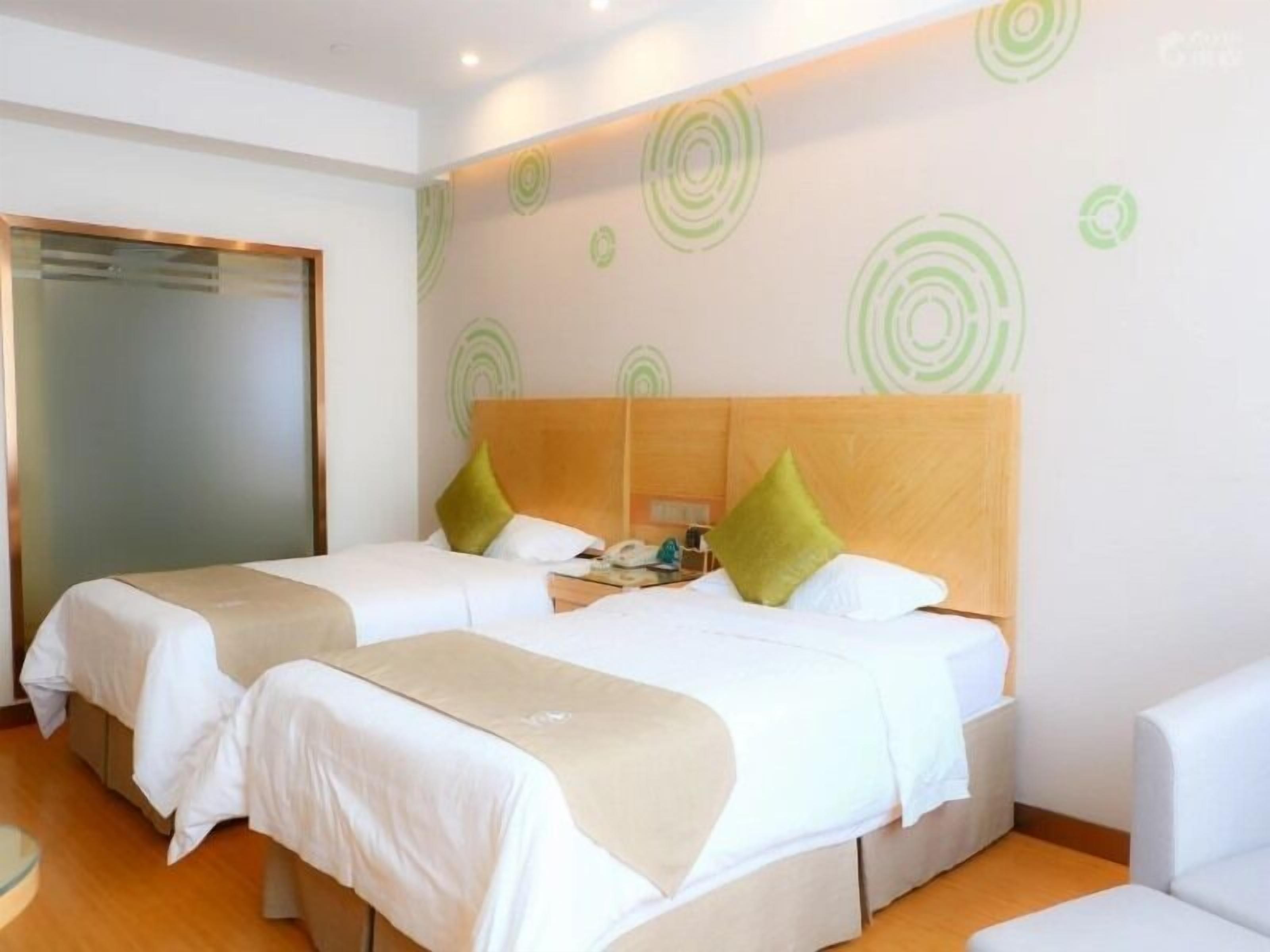 Ein Hotelzimmer mit zwei Betten, einem Holzkopfende und einem grünen, runden Wanddekor.