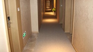 A hotel corridor with carpeted floors and wooden walls. - GreenTree Eastern Shaoxing Keqiao Jindizizaicheng Hotel (Shaoxing)