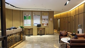A modern hotel lobby with a reception desk, seating area, and lockers. - GreenTree Eastern Shaoxing Keqiao Jindizizaicheng Hotel (Shaoxing)