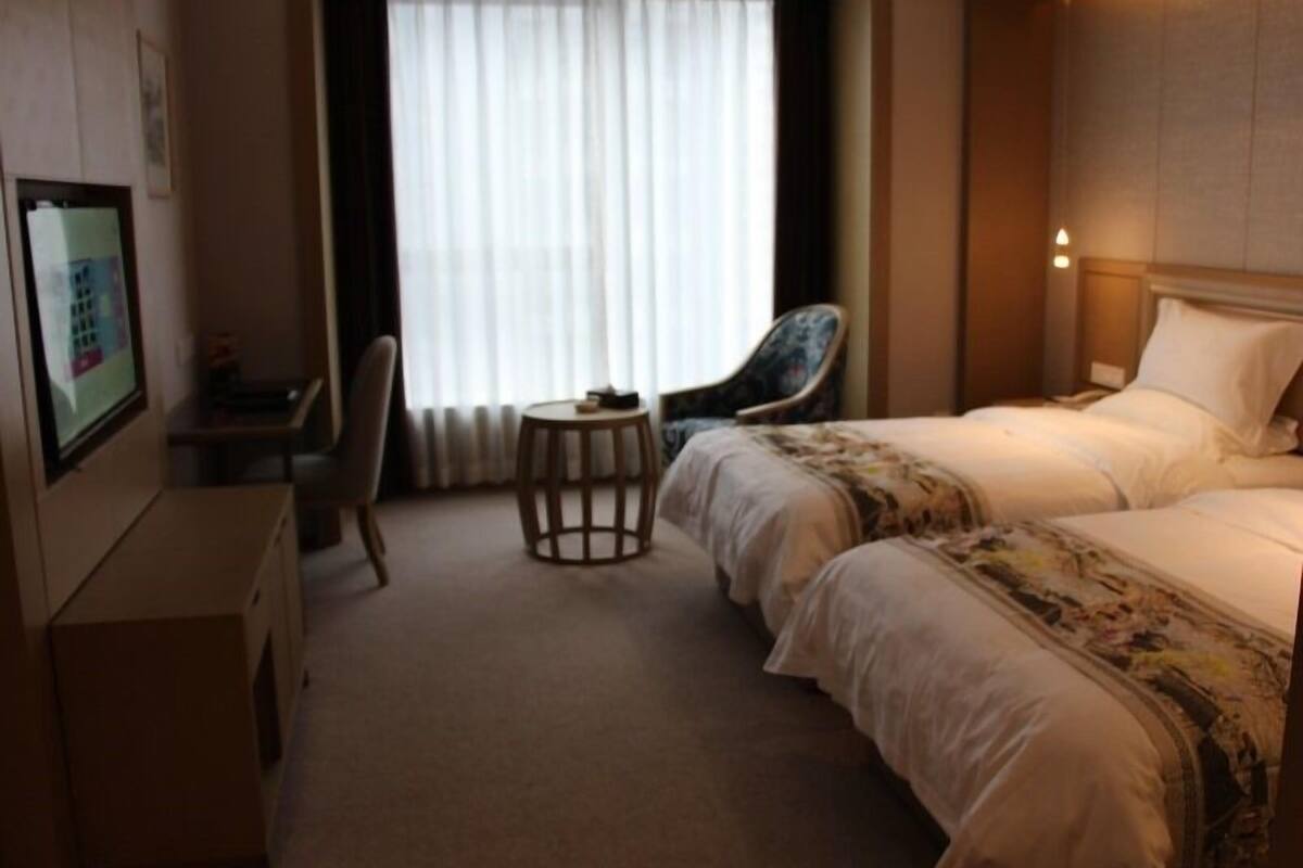 Une chambre d’hôtel avec un lit, un bureau, une chaise et une petite table.