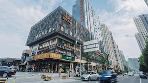 A multi-story building with various storefronts on the ground floor, including a visible restaurant and a store with a green sign. - GreenTree Eastern Shaoxing Keqiao Jindizizaicheng Hotel (Shaoxing)