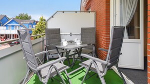 A balcony with a table and chairs, a yellow awning, and a view of neighboring houses. - Vacation apartment 2 - House Wiederkehr in Bensersiel (Esens)