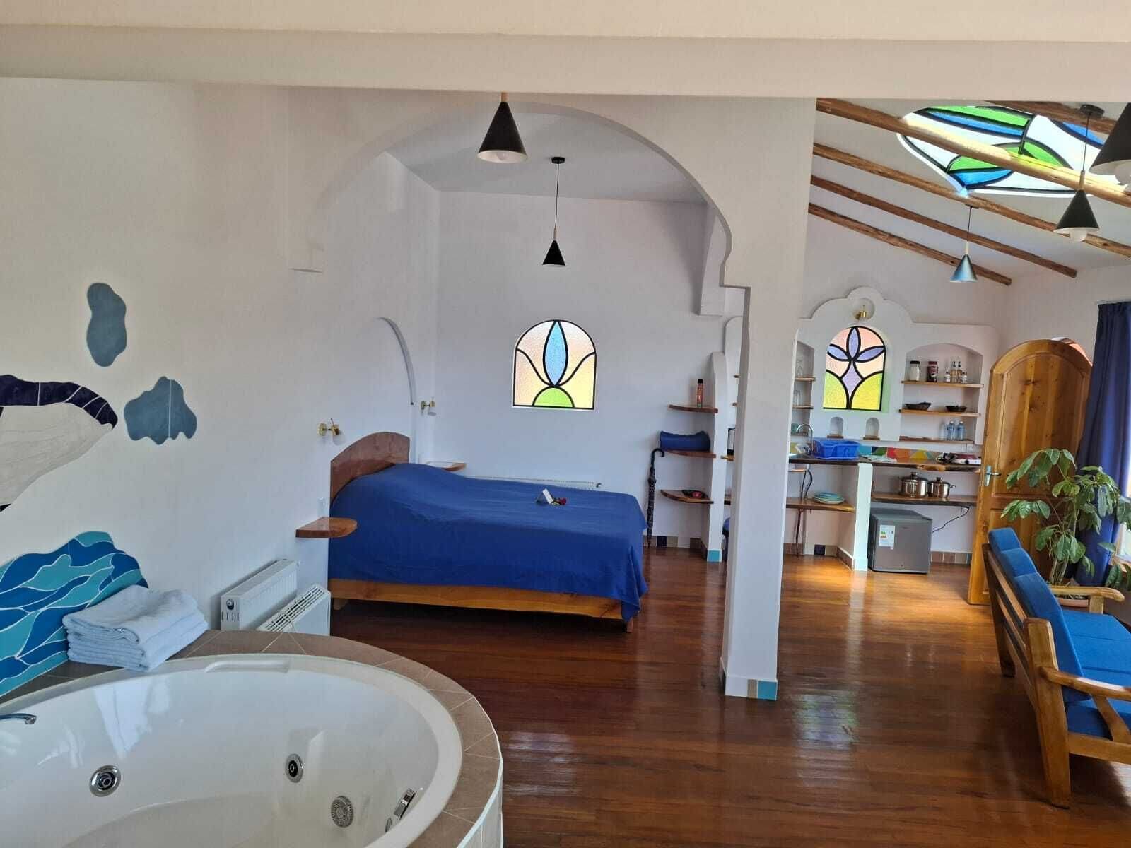 A room with a bed, a bathroom with a bathtub, and a kitchenette.