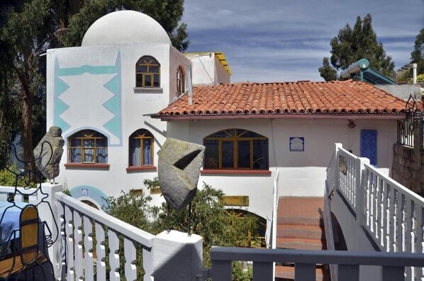 Un edificio con fachada blanca, techo de tejas rojas y barandilla blanca.
