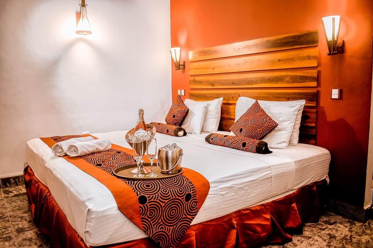 A hotel room with a large bed, wooden headboard, and a tray with towels and a bottle.
