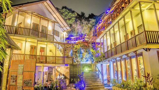 A multi-story building with a central staircase, balconies, and a sign indicating a pub. - Sizzlers Hub - Hostel (Kandy)