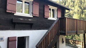 Un bâtiment en bois doté d’un balcon, de fenêtres avec volets et d’un chemin en pierre.