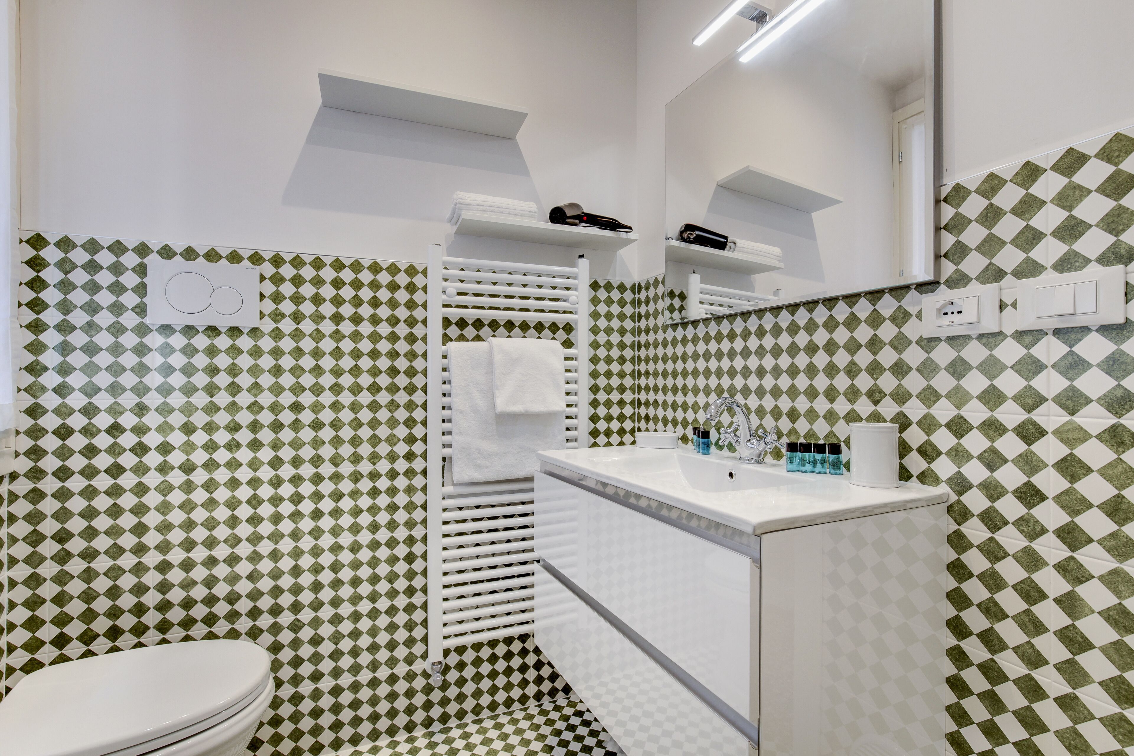 A bathroom with a white toilet, a sink with a mirror, and a towel rack.