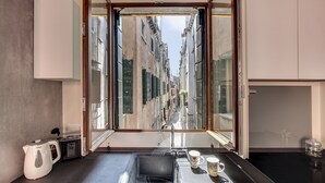 Una cuina moderna amb una finestra gran, un bullidor, una cafetera i un rentapeus.