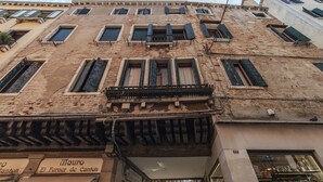 Un edifici històric amb diverses finestres, algunes amb persianes, i un aparador visible amb senyalització.