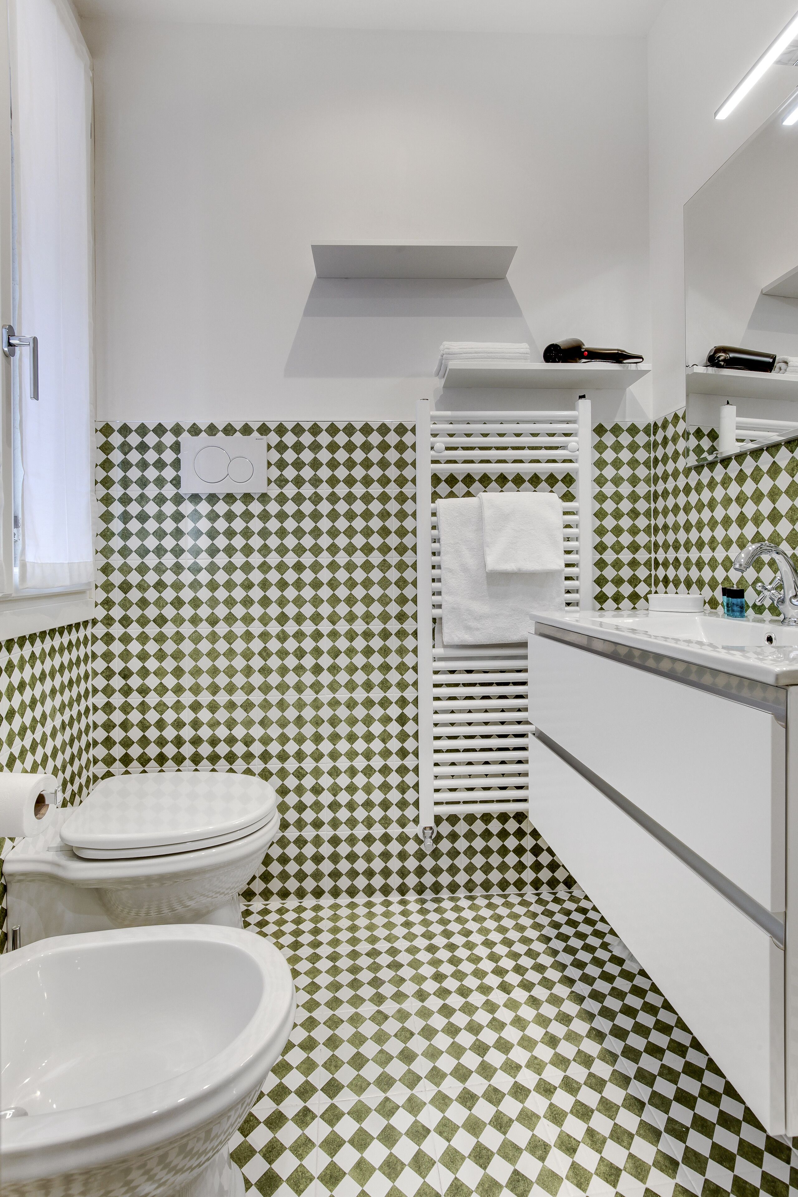 A bathroom with a checkered floor pattern, a white toilet, a sink, and a mirror.