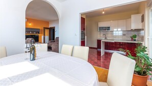 A modern living space with a dining area, kitchen, and a red-tiled floor. - Beach front home in Kostrena (Kostrena)
