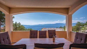 A terrace with a table and chairs, overlooking a scenic view of the sea and mountains. - Beach front home in Kostrena (Kostrena)