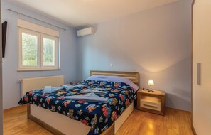 Cozy retreat with a single bed, light blue walls, and a window overlooking lush greenery.