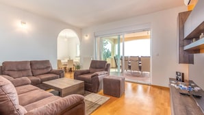 A spacious living area with a brown leather sofa set, a coffee table, and a dining area visible through an archway. - Beach front home in Kostrena (Kostrena)