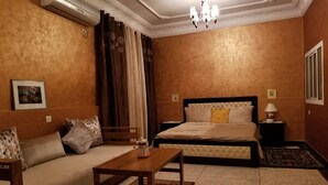 A hotel room with a bed, a sofa, a wooden table, and a nightstand with a lamp. - Villa of your dreams .. (Agadir)